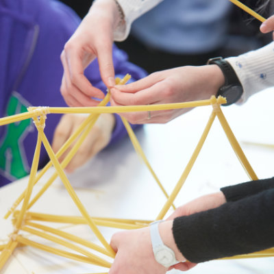 Students working together on a construction activity with straws.